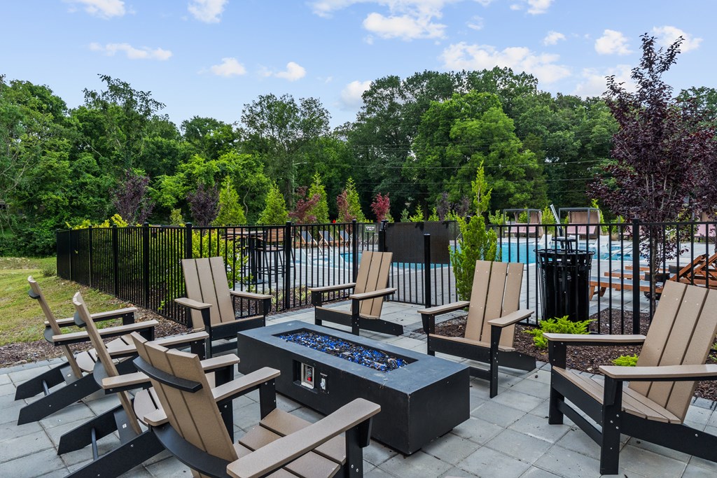 A patio with chairs and a table with a pool in the background.