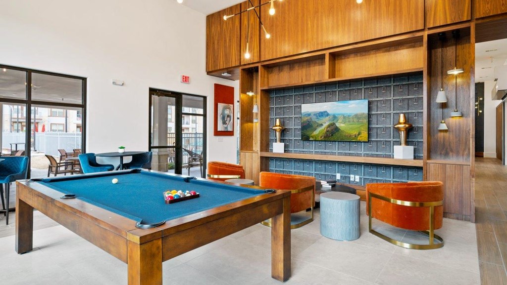 a pool table in a game room with chairs and a tv