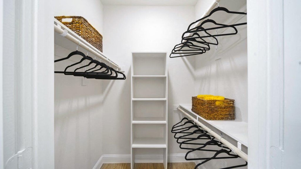 a walk in closet with white walls and shelves with black shoes