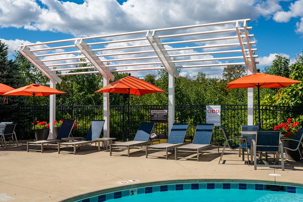A pool area with sun loungers and umbrellas.