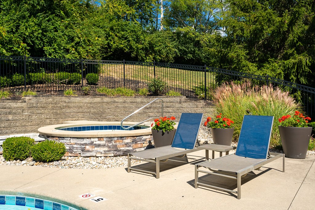 A pool with a stone border and a fence behind it.