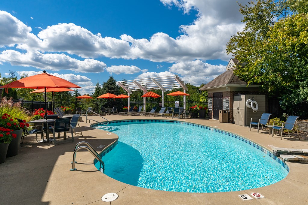 A swimming pool surrounded by chairs and umbrellas.