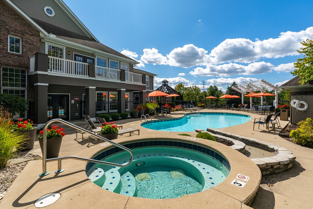 A large outdoor swimming pool with a hot tub in the middle of it.