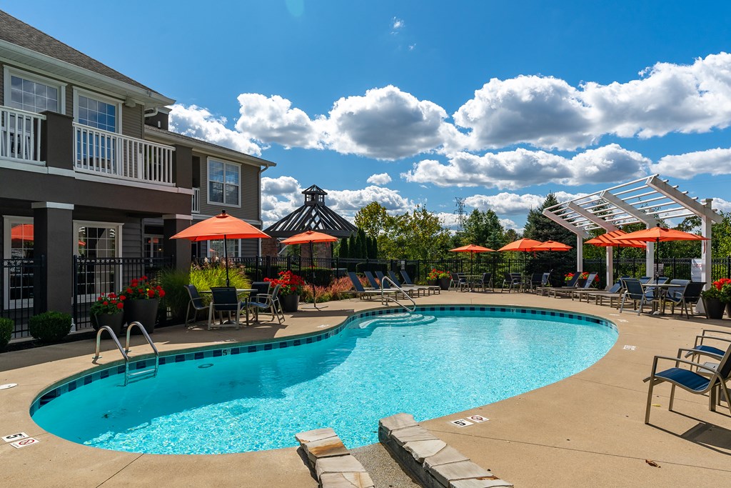 A large swimming pool surrounded by lounge chairs and umbrellas.