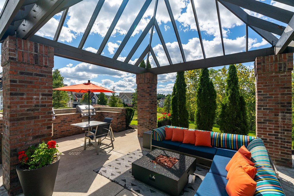 A patio with a couch, table, and fireplace under a pergola.