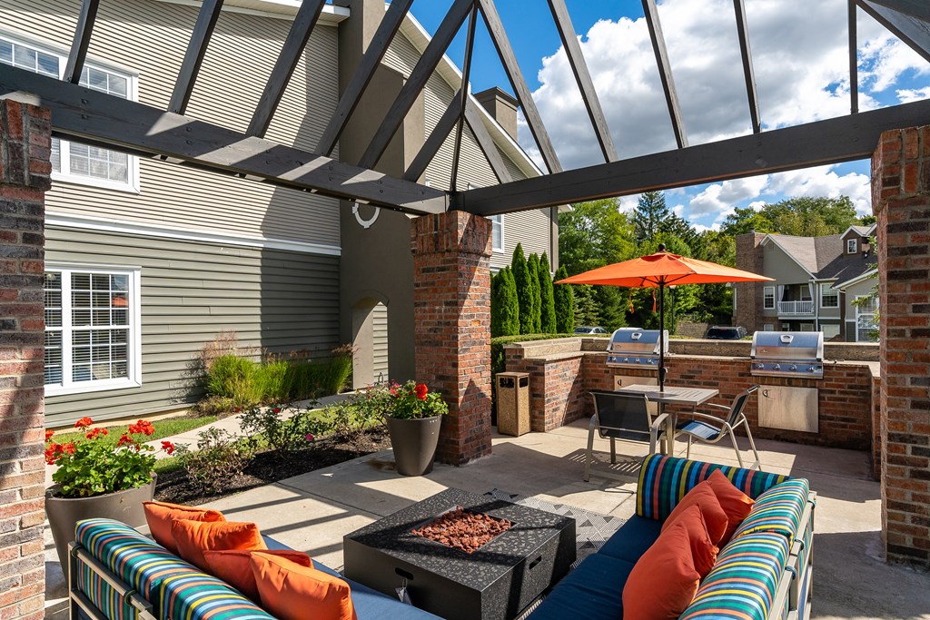A patio with a table, chairs, and a fire pit.