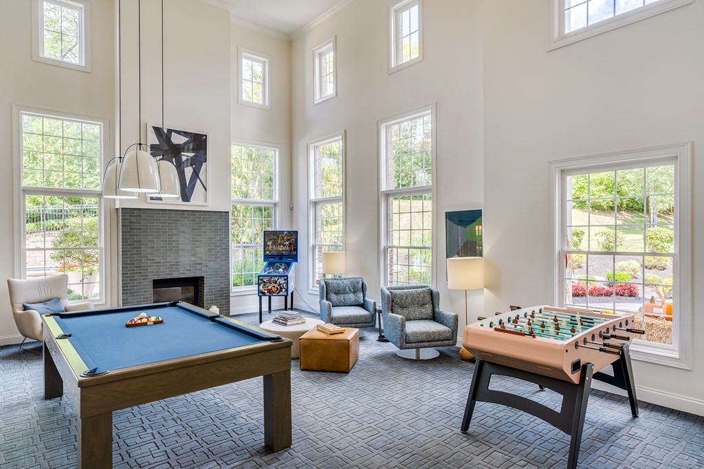A pool table and a foosball table are in a large room with a fireplace.