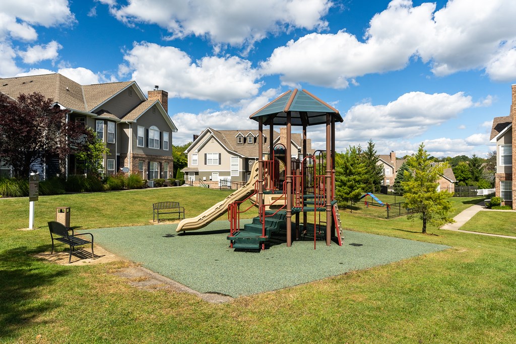 A playground with a green slide and a red swing set.
