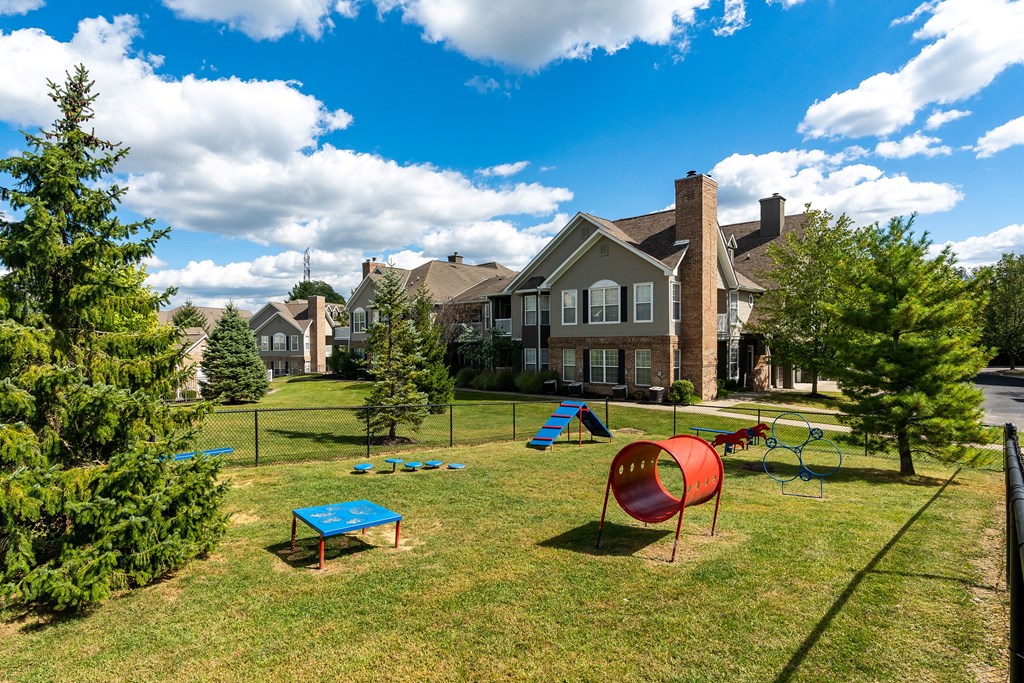A playground with a red slide and blue table is in the foreground of a residential area.