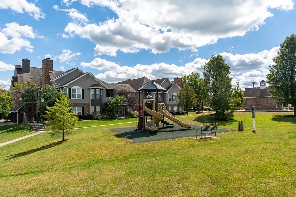 A playground with a slide and a swing set in a grassy area.
