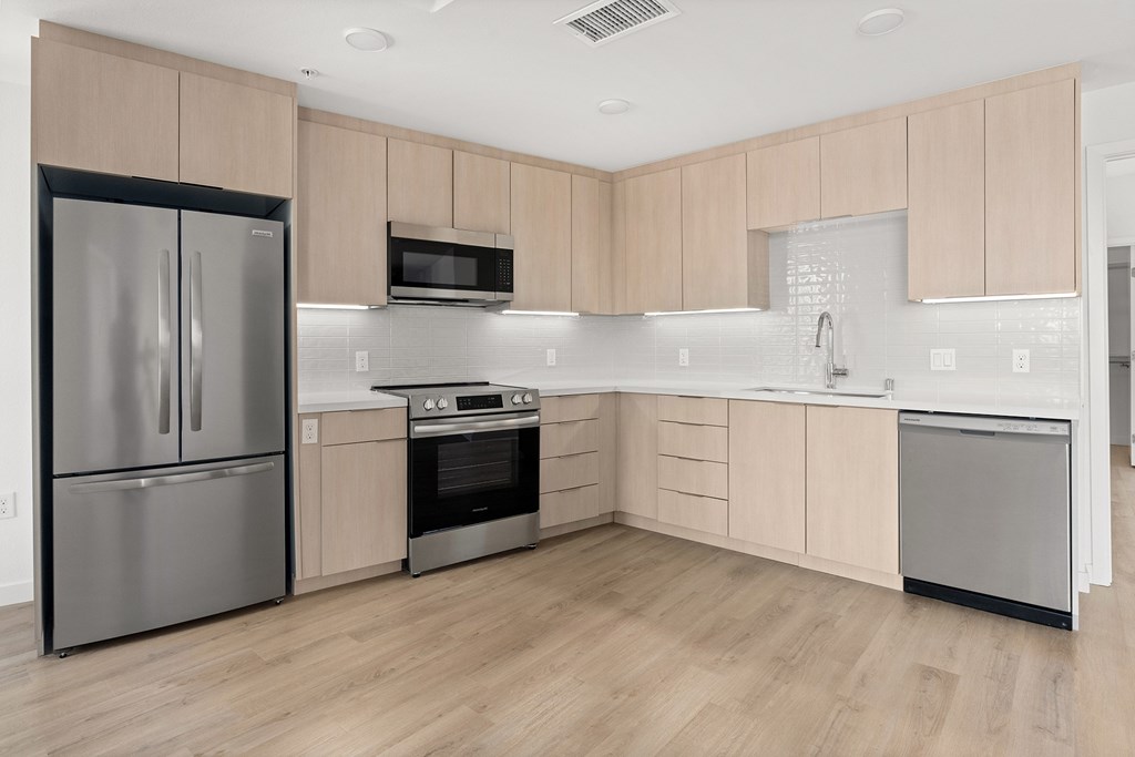 A kitchen with a refrigerator, oven, microwave, and sink.