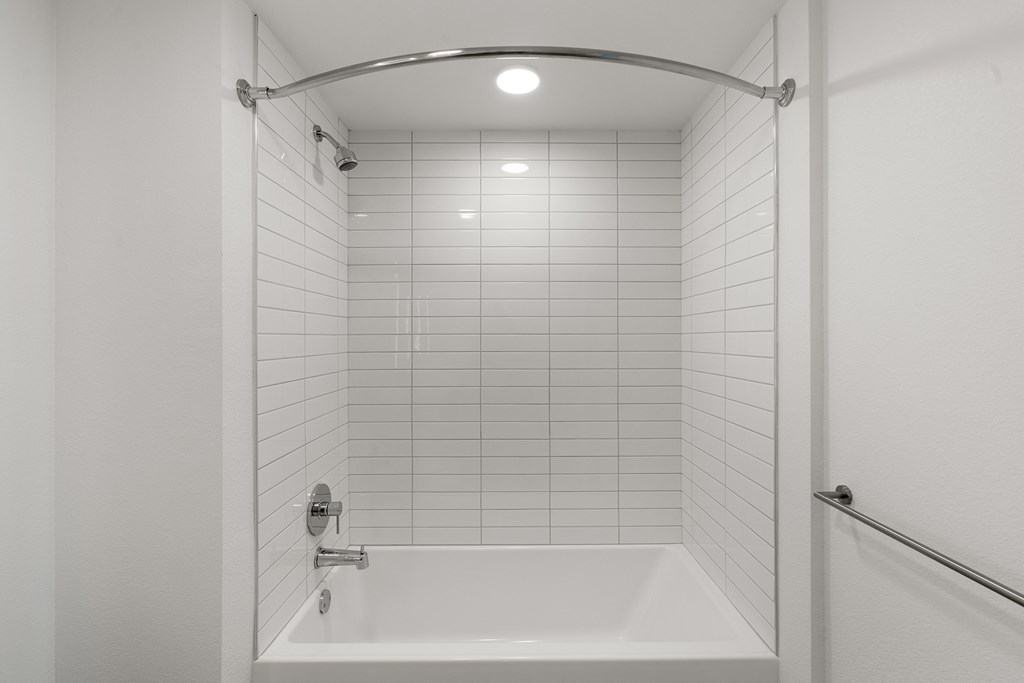 A white bathroom with a white tub and white tiles.
