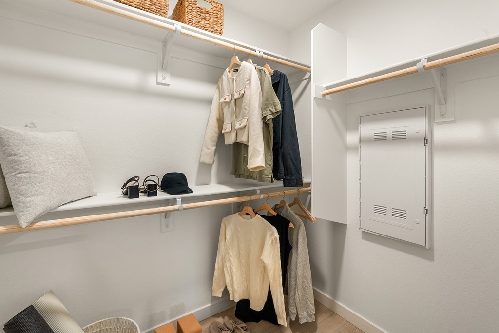 A white closet with clothes hanging and a white door.