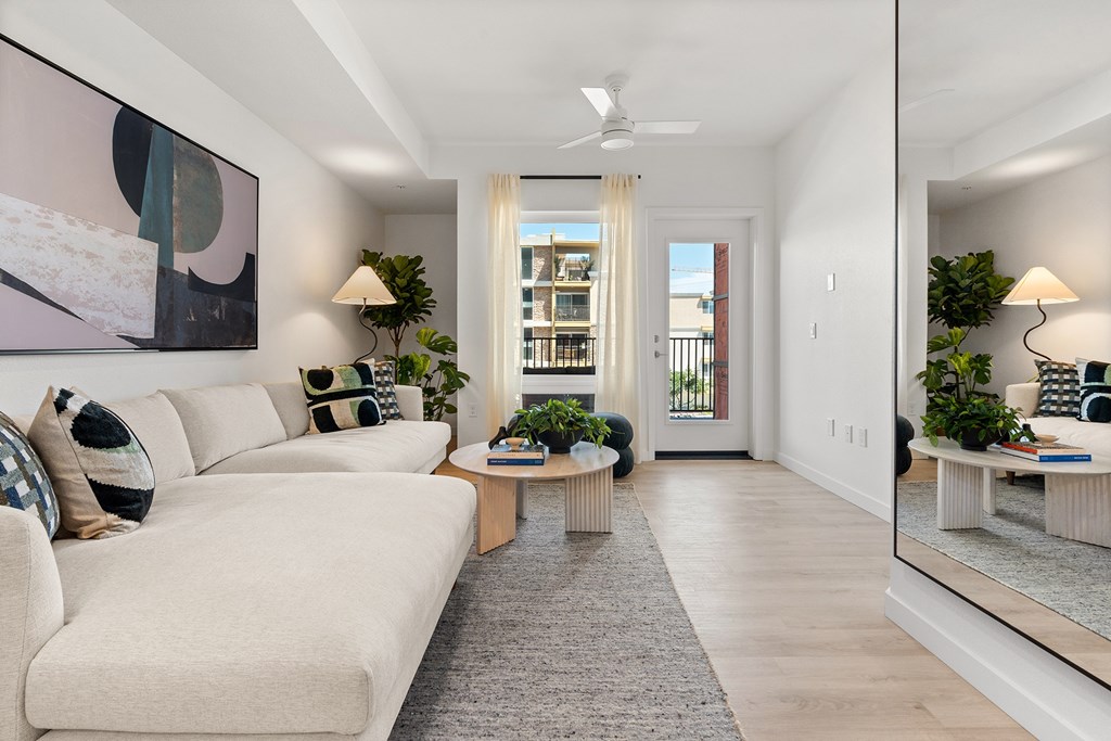 A living room with a white couch and a painting on the wall.