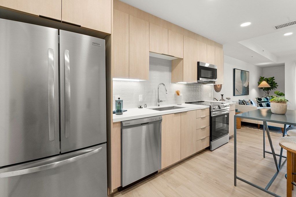A modern kitchen with a stainless steel refrigerator and wooden cabinets.