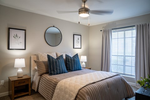 A bedroom with a large bed and a ceiling fan.