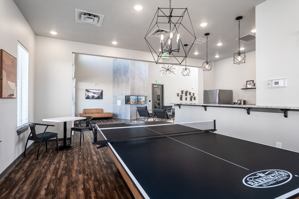 an open living room with a ping pong table and a kitchen with a tv