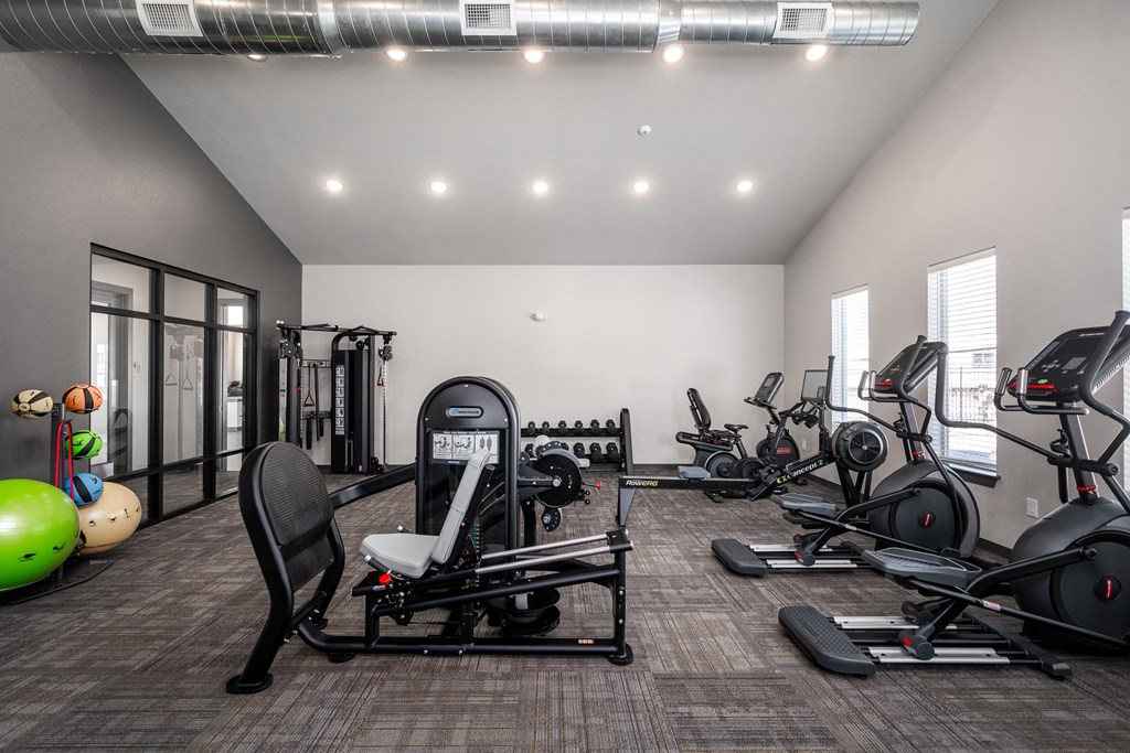 a gym with cardio machines and other exercise equipment in a building with windows