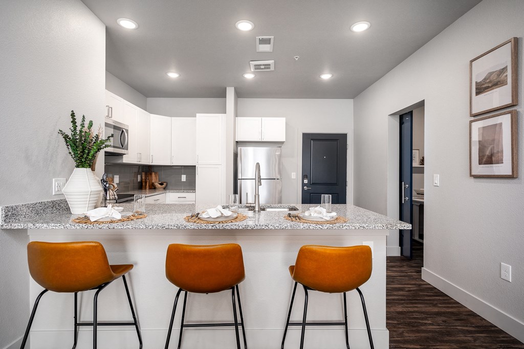 an open kitchen with a counter top with three stools