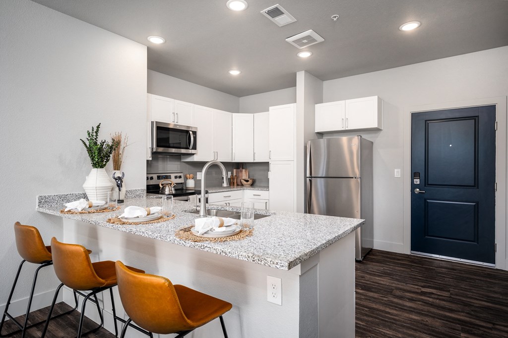 a kitchen with a marble counter top and a stainless steel refrigerator