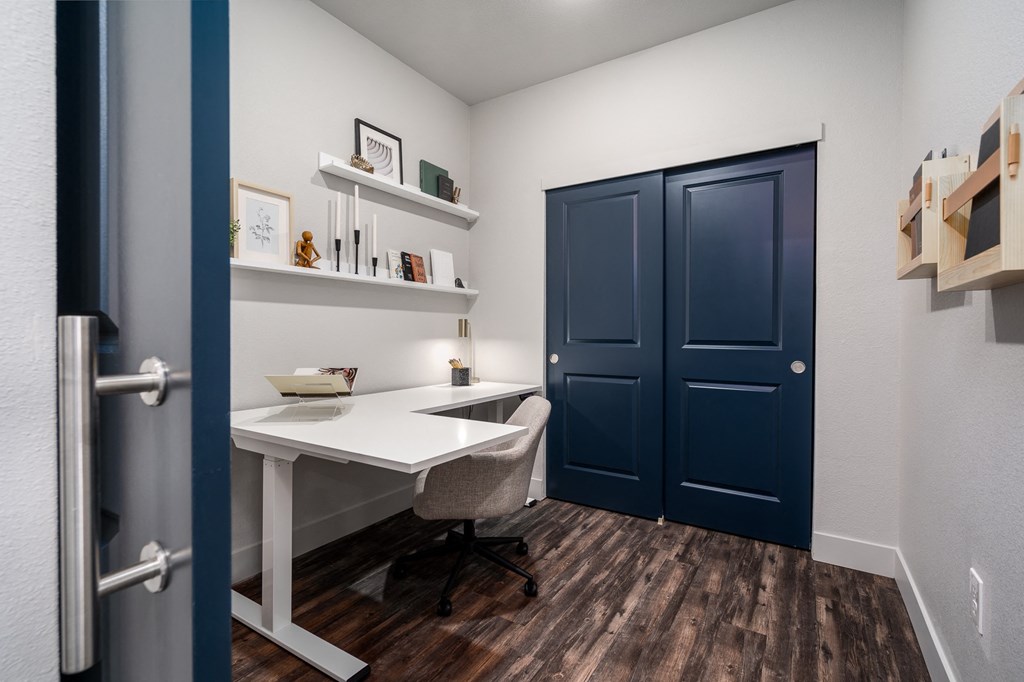 a home office with a white desk and a blue door