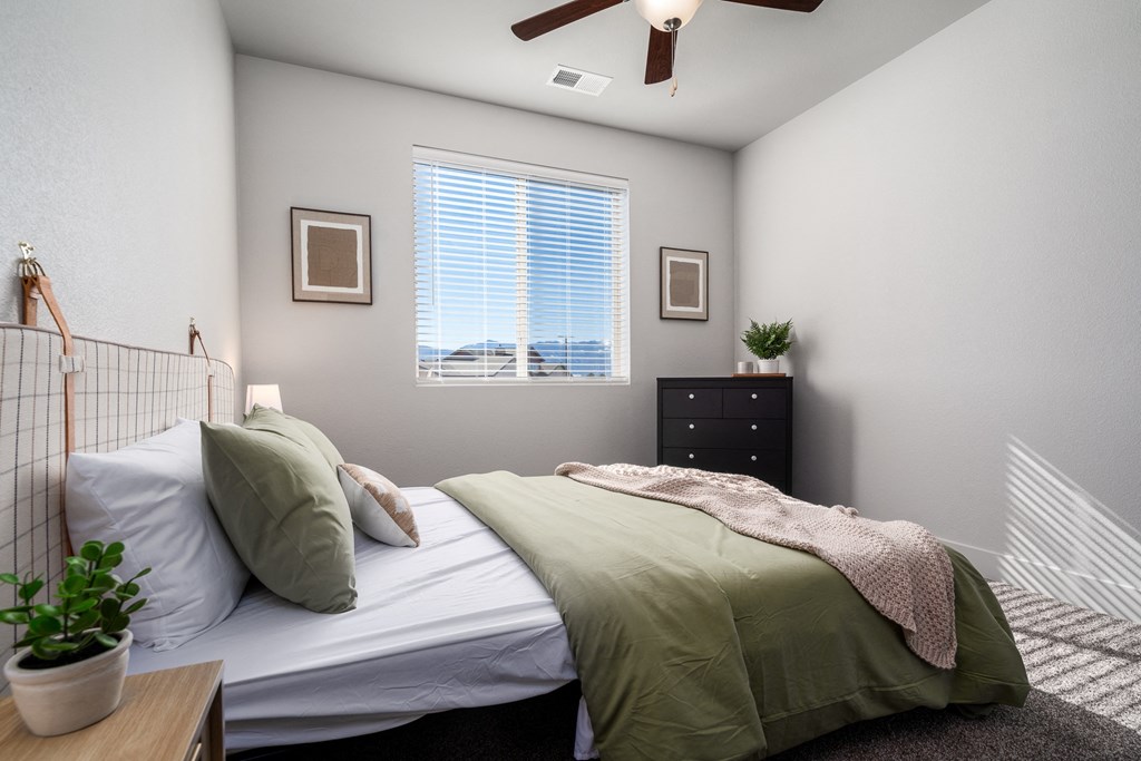 an empty bedroom with a bed and a ceiling fan