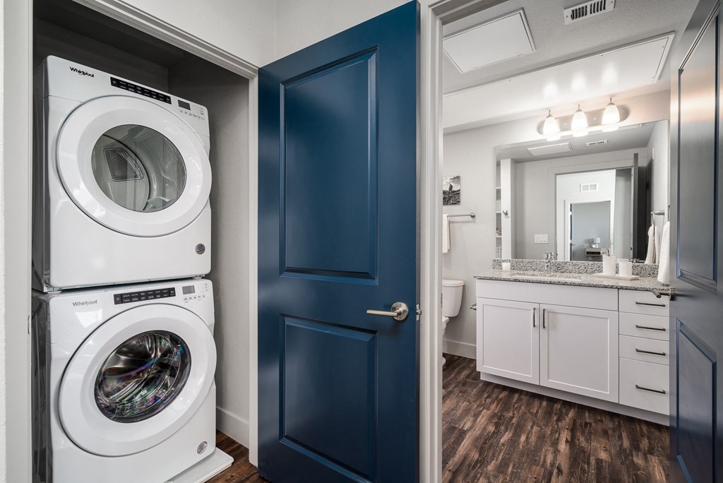 a white washer and dryer in a bathroom with a blue door