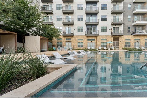 A large swimming pool in front of apartment buildings.