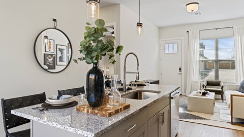 an open kitchen and living room with an island and a sink