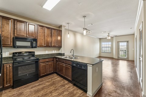 A kitchen with dark wood cabinets and black appliances.