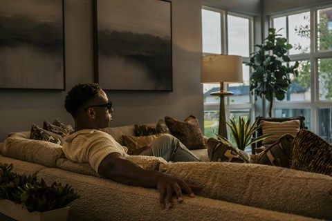 A man is lounging on a couch in a well-decorated room.
