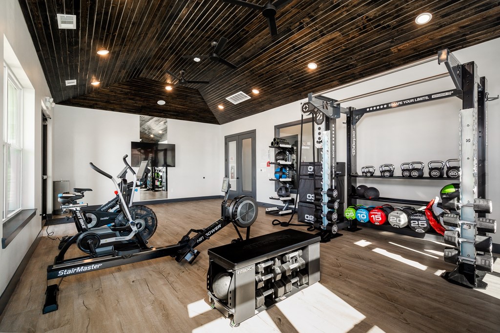a home gym with exercise machines and weights on a wooden floor