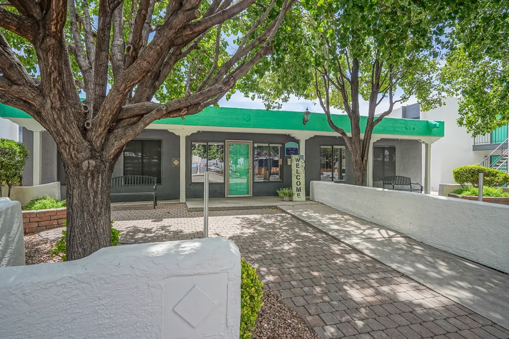 a building with a green roof and trees in front of it