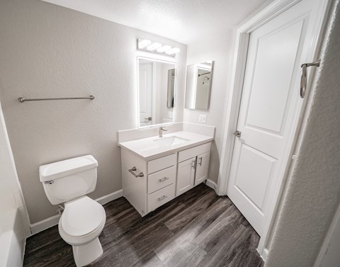 A white bathroom with a toilet, sink, and mirror.