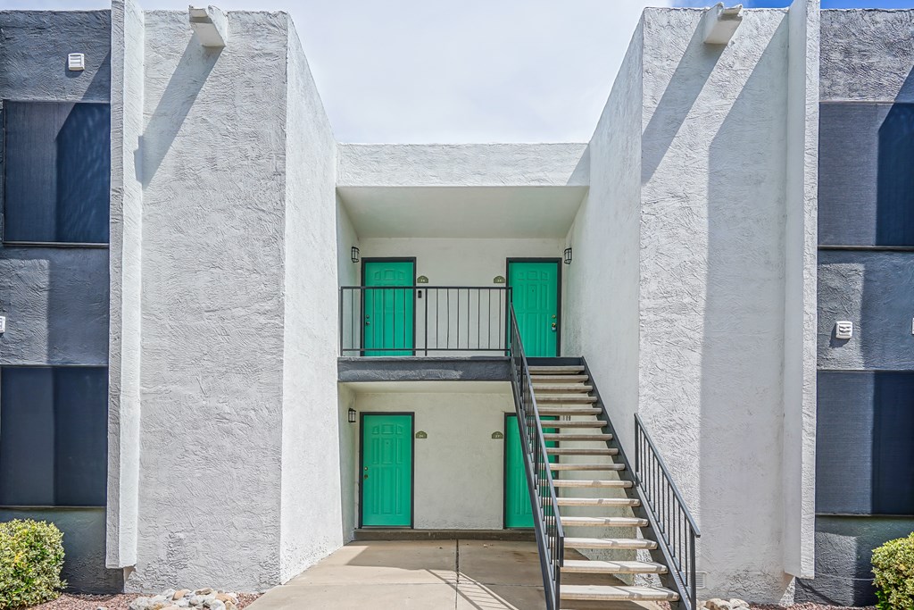 the front of a building with green doors and stairs