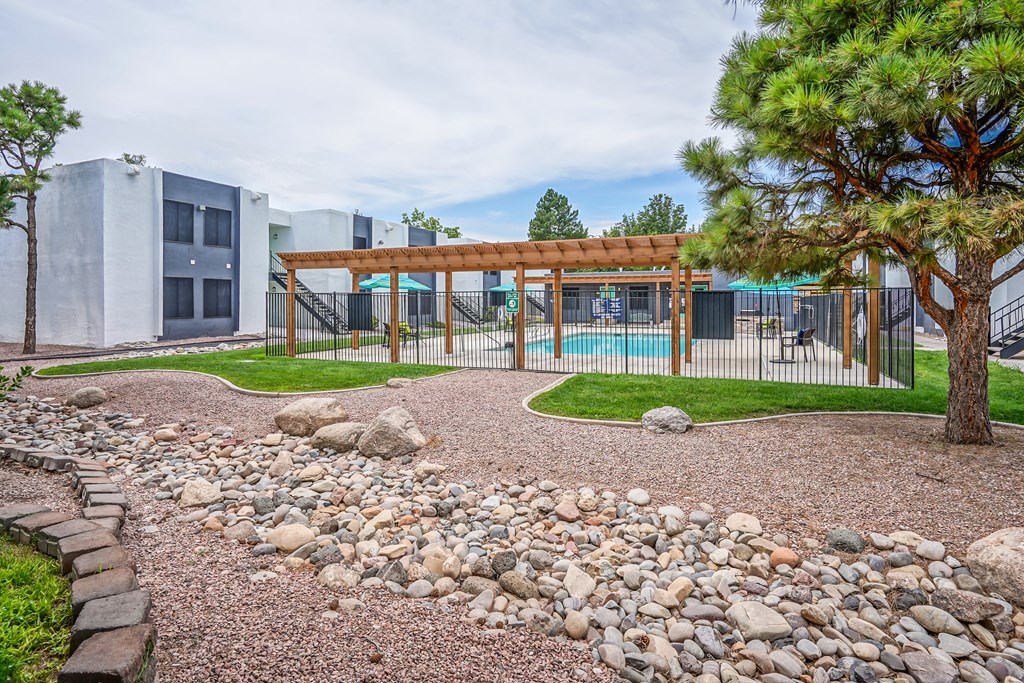 a courtyard with rocks and a fence with a swimming pool