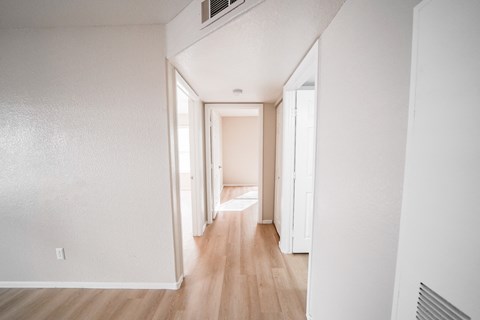 A long hallway with white walls and wood floors.