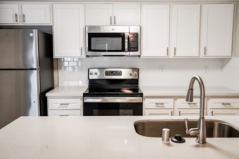 A kitchen with a stainless steel refrigerator, a microwave, and a stove top oven.