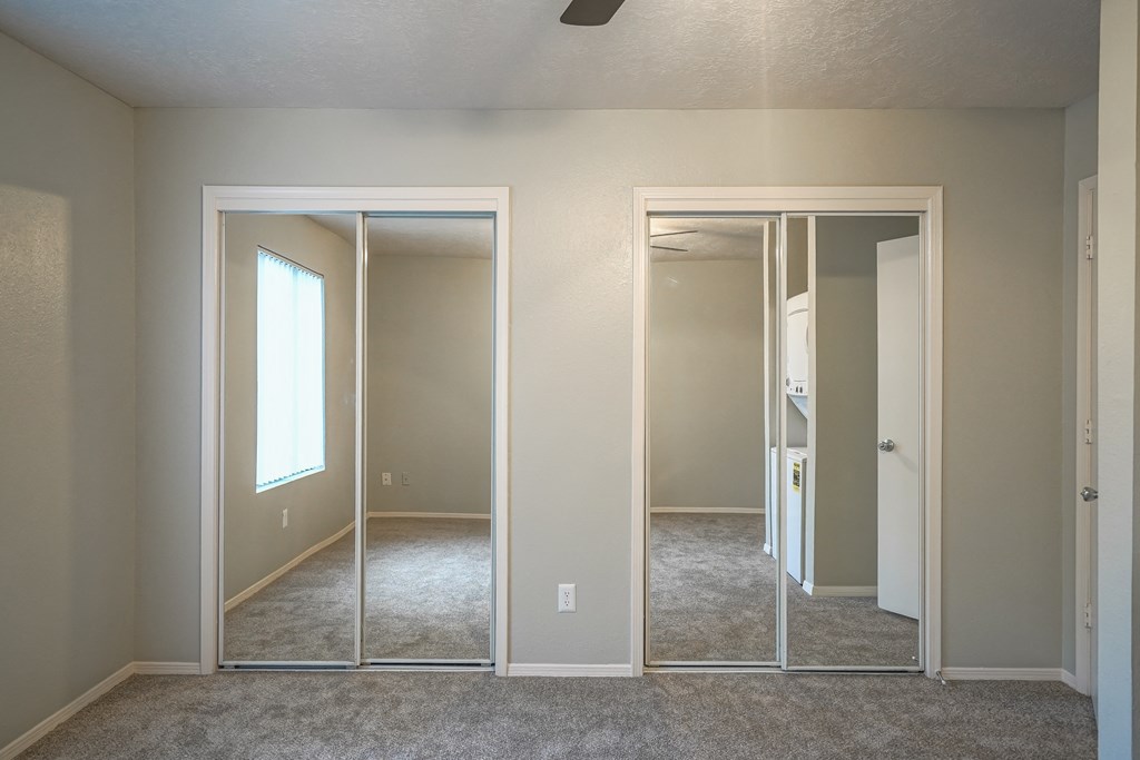 an empty bedroom with mirrored doors and a carpeted floor