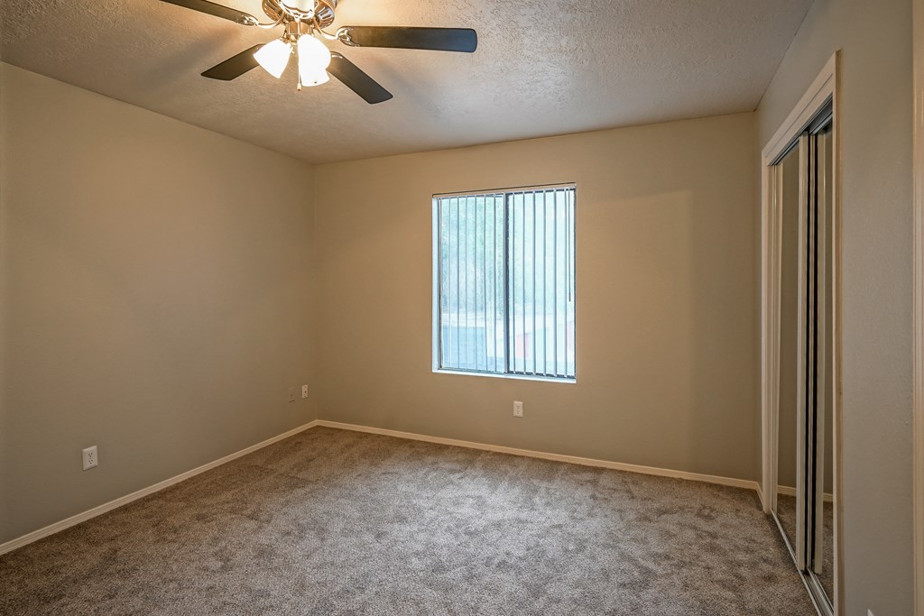 an empty living room with a ceiling fan and a window