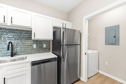 A kitchen with a refrigerator, dishwasher, and sink.