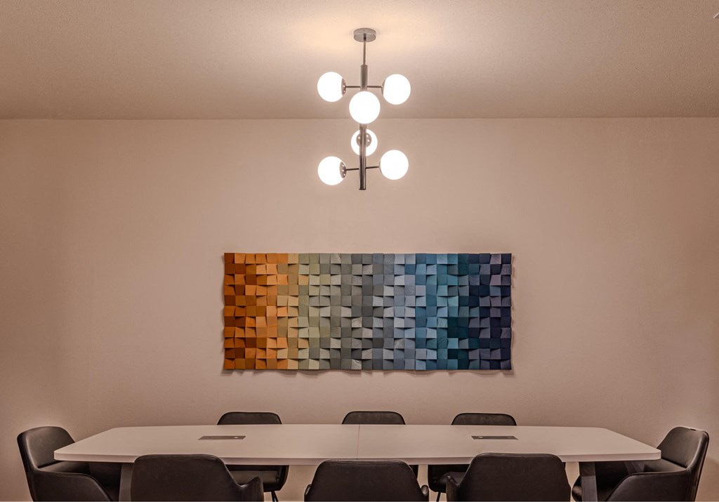 a conference room with a table and chairs and a painting on the wall