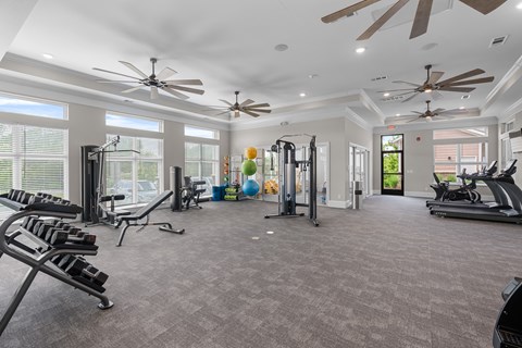 A spacious gym with various exercise equipment and a ceiling fan.