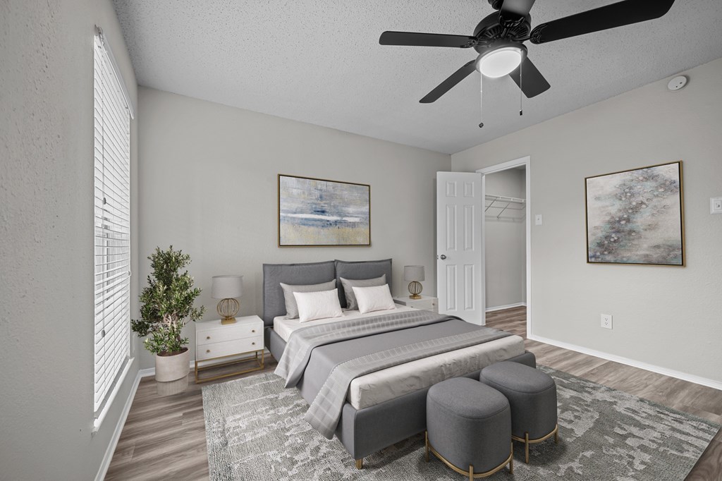 A bedroom with a large bed, a ceiling fan, and a painting on the wall.