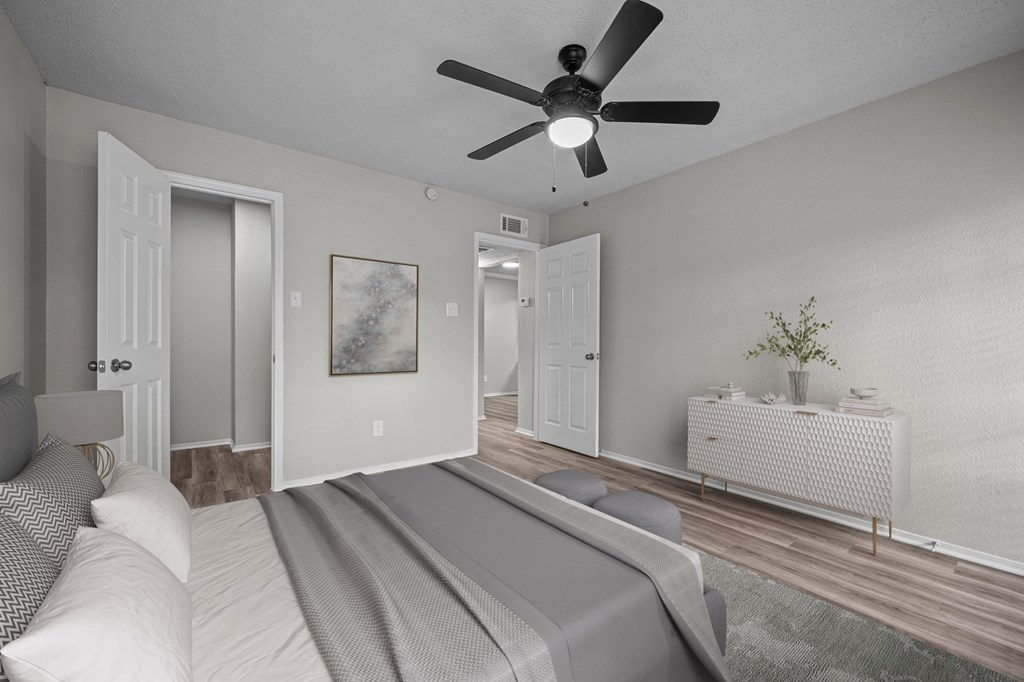 A bedroom with a bed, a ceiling fan, and a nightstand.