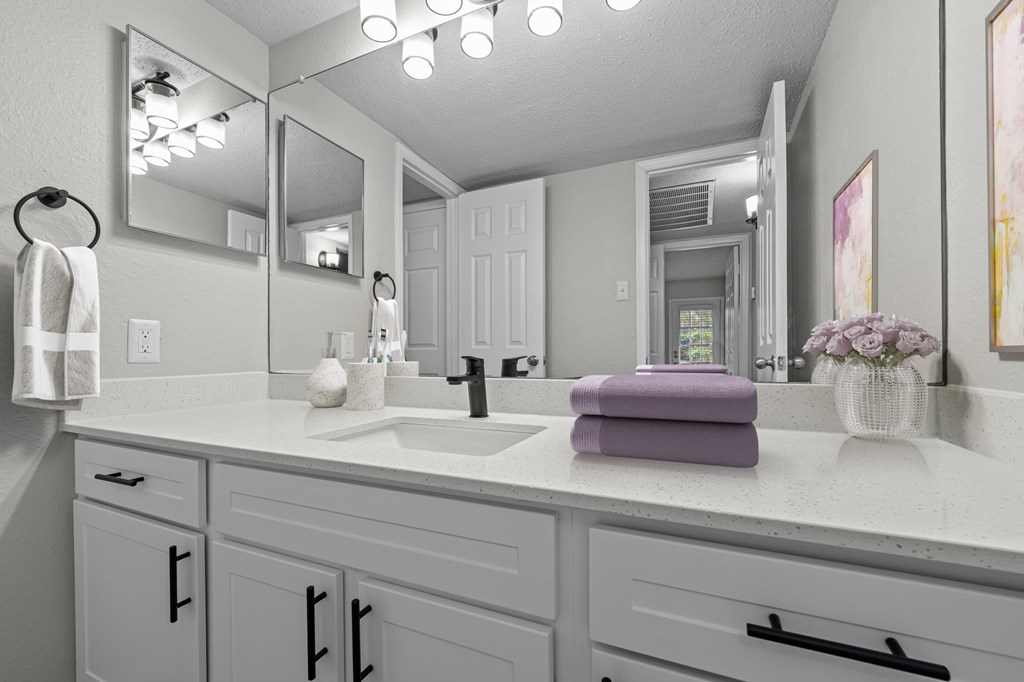 A bathroom with a white counter top and a purple towel.