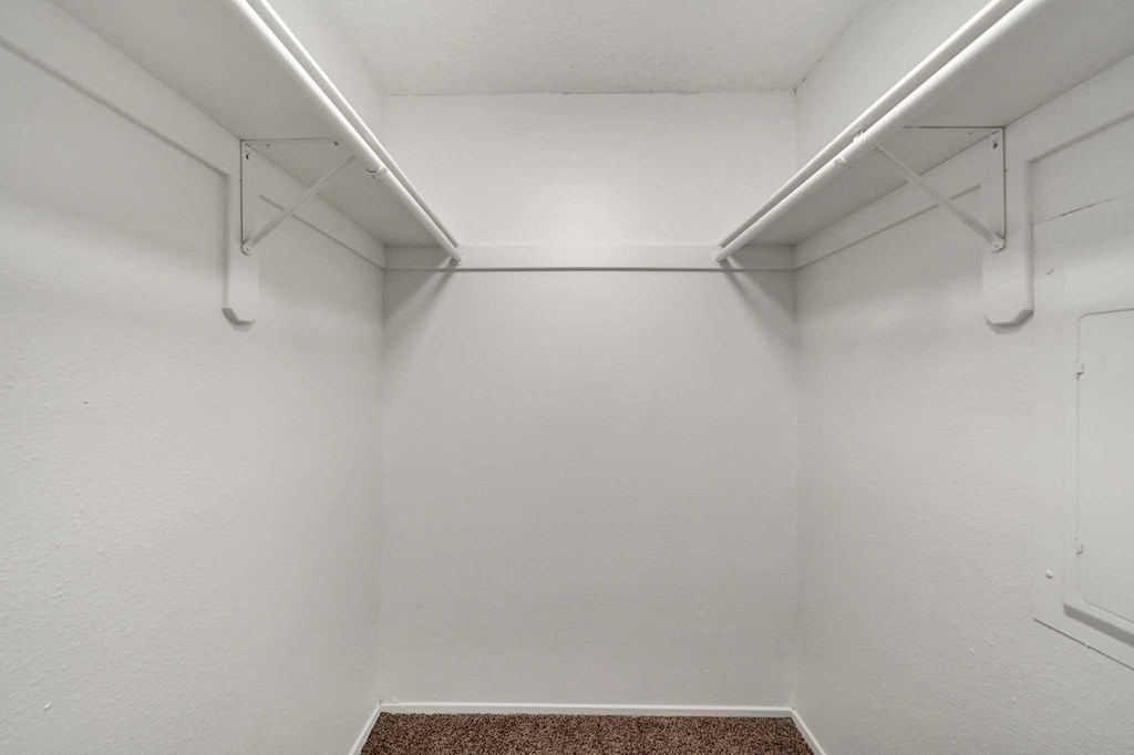 a walk in closet with white walls and a carpeted floor