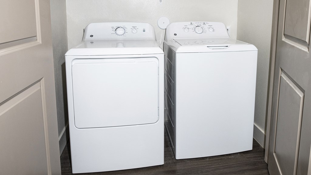 two washers and dryers in a small room with a door