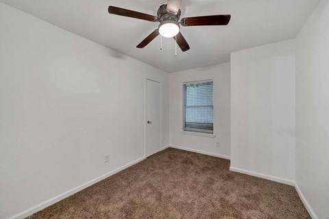 a bedroom with white walls and a ceiling fan