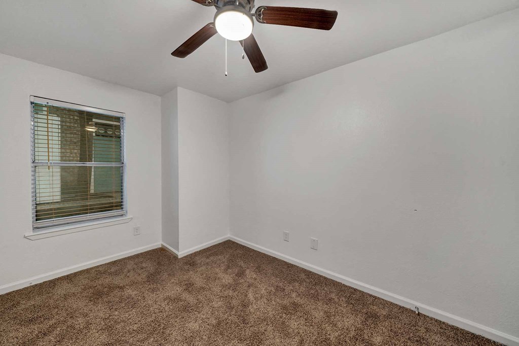 an empty room with a ceiling fan and a window